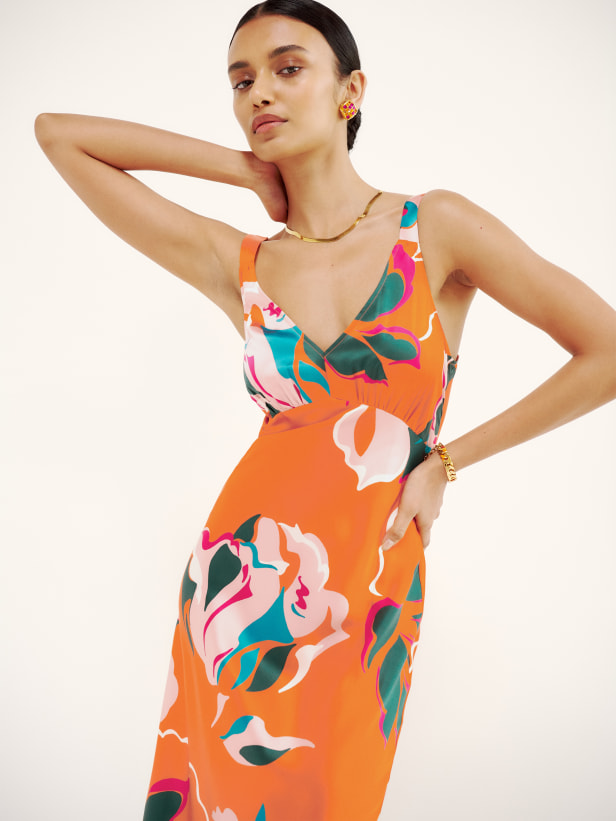 Reformation silky Daytona dress is a midi length, slip dress with a deep v neckline in an orange based floral. There's ruching at the bust for a slightly fancier look. It's relaxed fitting throughout but still has a cute shape to it.