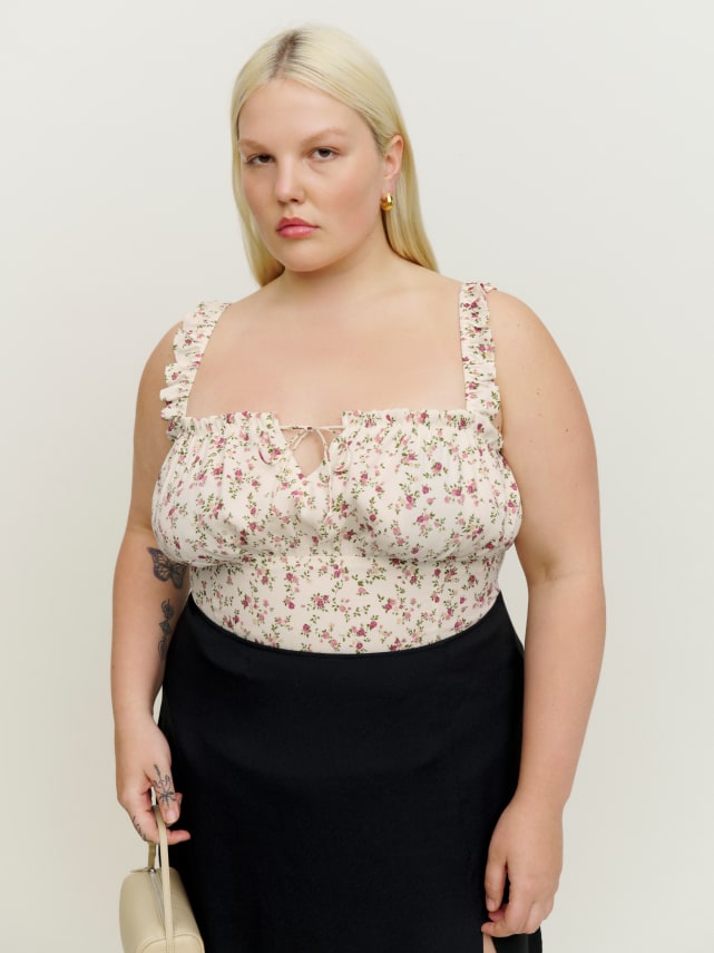 Slim fitting white top with ditsy floral. Adjustable tie at the neckline that you can adjust to your liking. It has a fully smocked back with elastic shoulder straps so it's comfortable and easy to get in and out of. Ruffled shoulder and neck. 