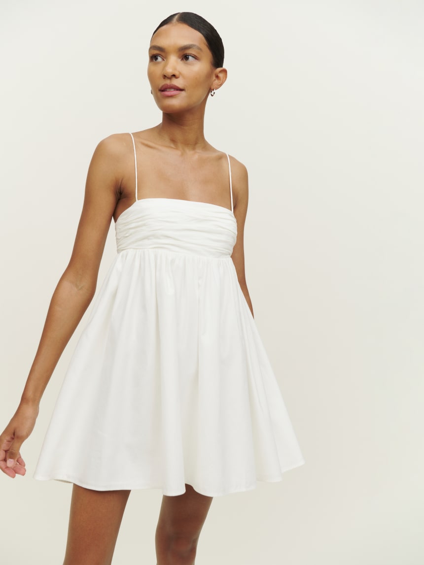 Reformation white organic cotton Catarina mini Dress has thin straps and a fitted bust with a flared skater skirt hem. 