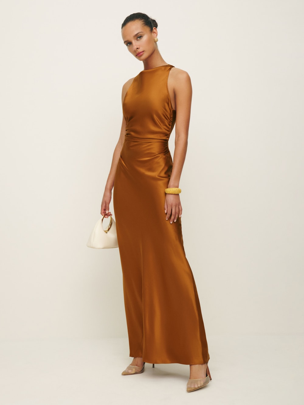2024 wedding guest outfits - Reformation Anaiis Silk maxi Dress in copper has a high neck, side ruching details and cross back detail. 