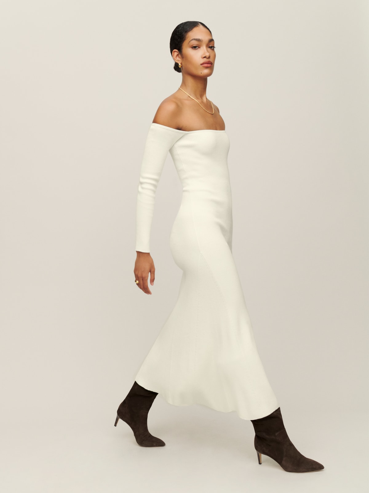 Reformation Symone dress in cream is an off the shoulder, fitted, knitted midi dress. It features long, fitted sleeves, a flared skirt, and can be worn day-to-night.