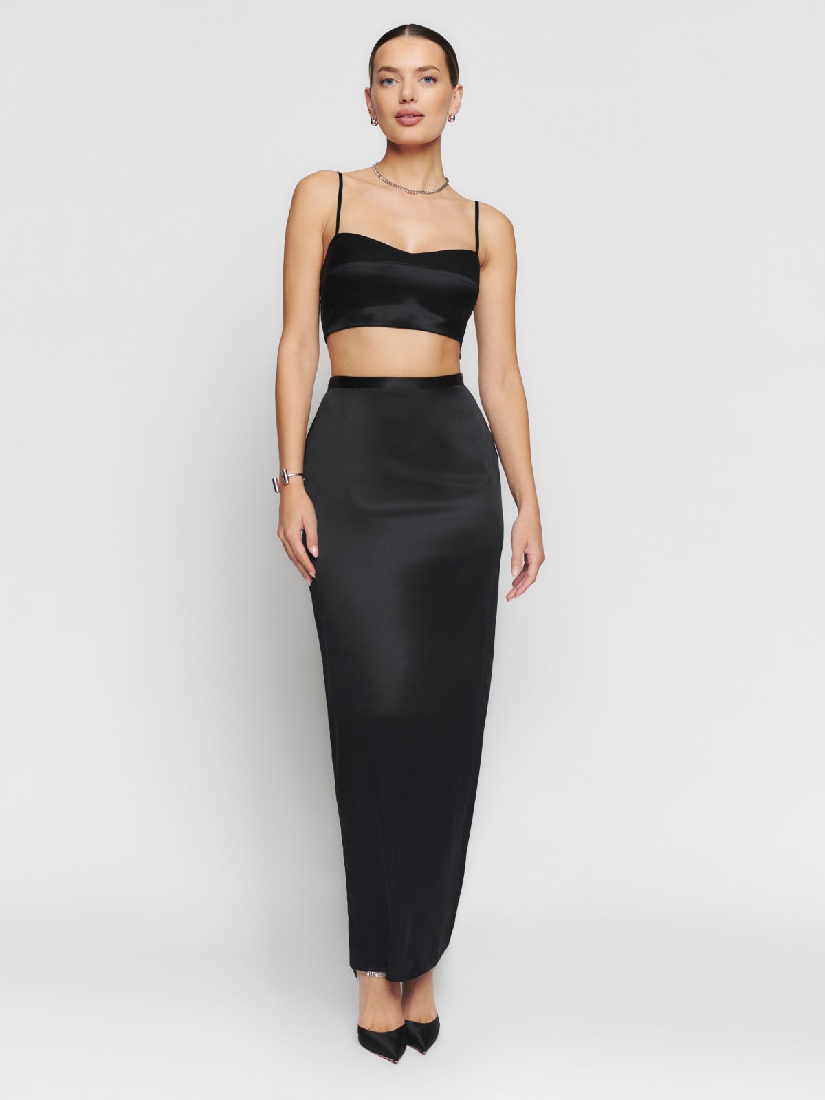 Reformation Isabella silk two-piece featuring a straight high waist maxi skirt in black silk and a cropped structured top with thin straps. 