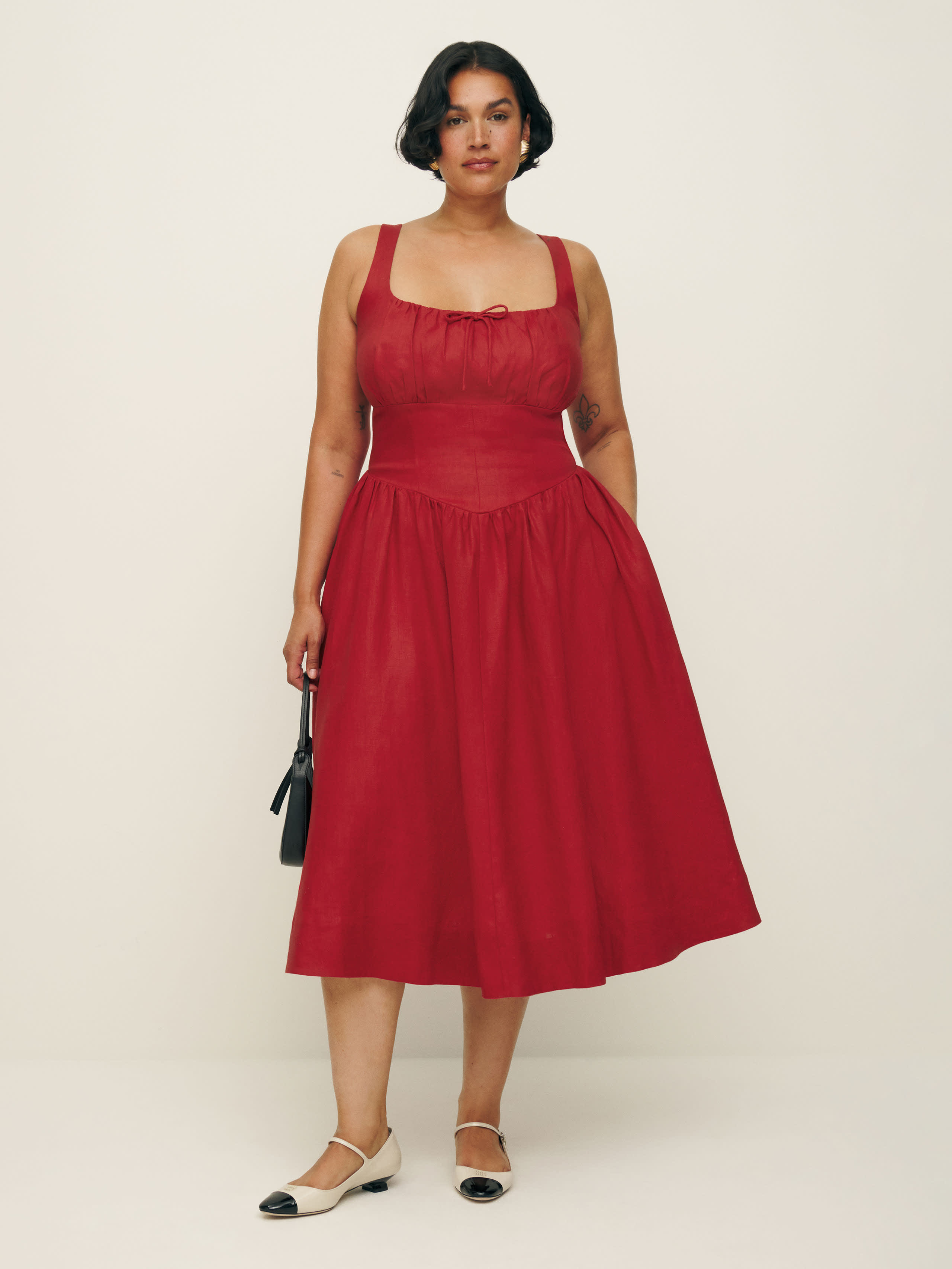A plus-size red linen midi dress with a cinched dress, full skirt, and small bow