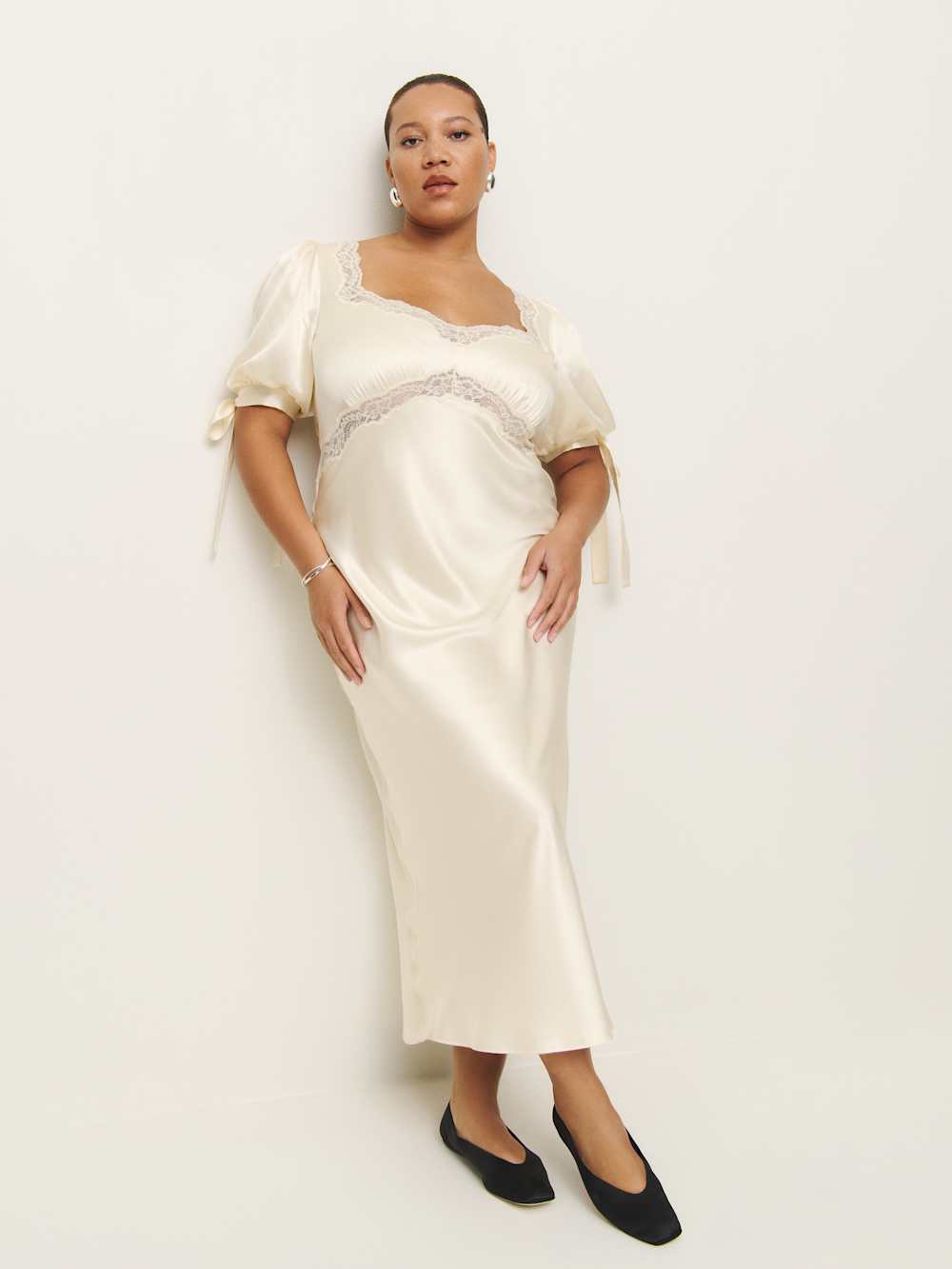 A plus-size white silk dress with lace trim and small bows on the sleeves